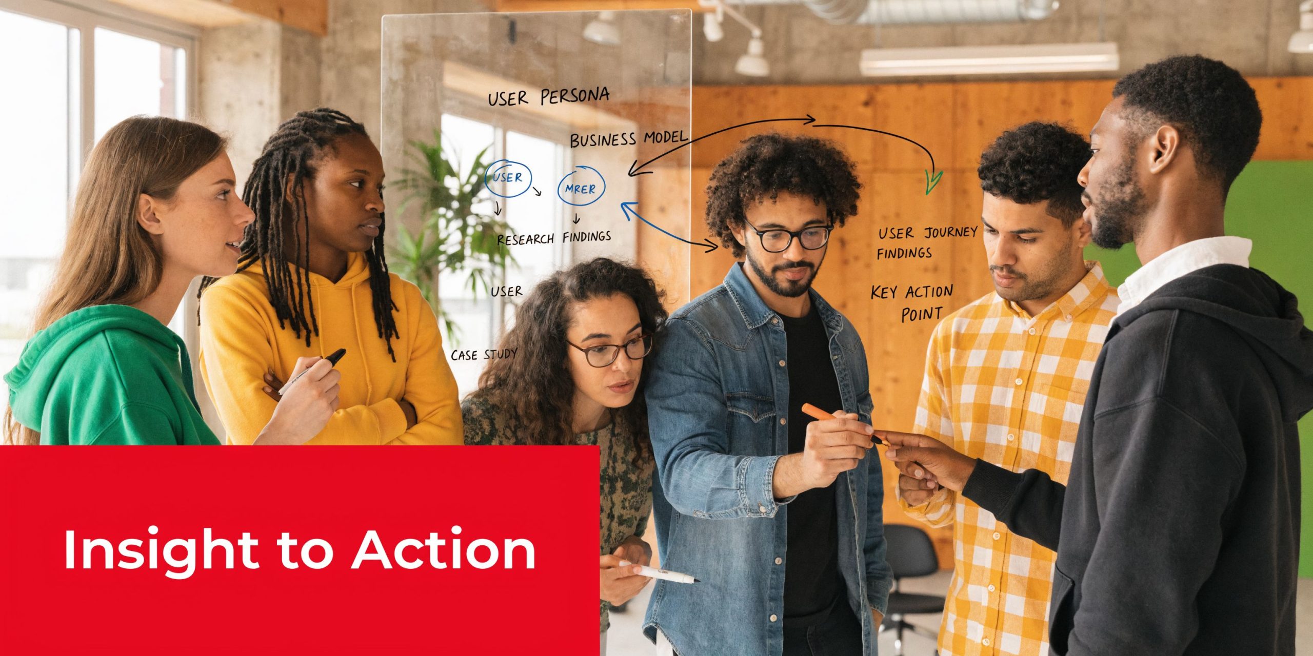 A diverse group of professionals collaborating in an office while brainstorming strategy on a glass board.
